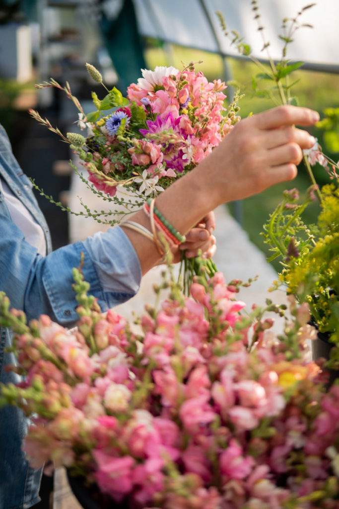 Mains d'une femme confectionnant un bouquet de fleurs dans les tons roses