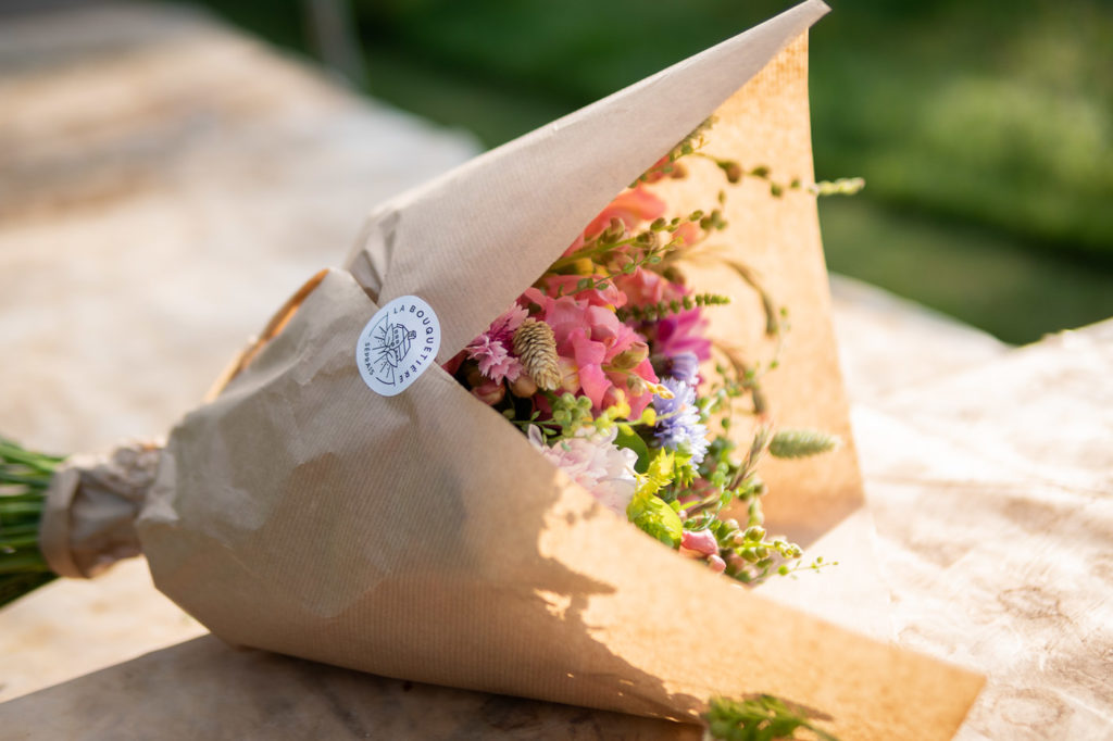 Bouquet de fleurs coupées et emballées dans un papier kraft, avec l'autocollant de LA BOUQUETIÈRE