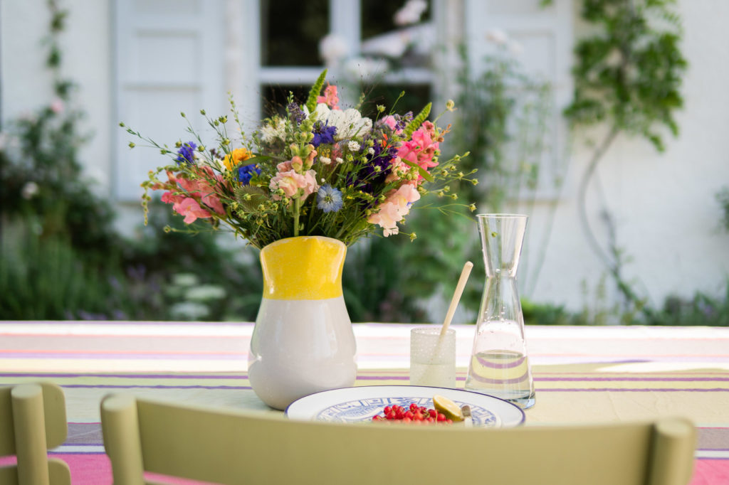 Bouquet de fleurs écologiques, locales et de saison, posées dans un vase sur une table d'extérieur