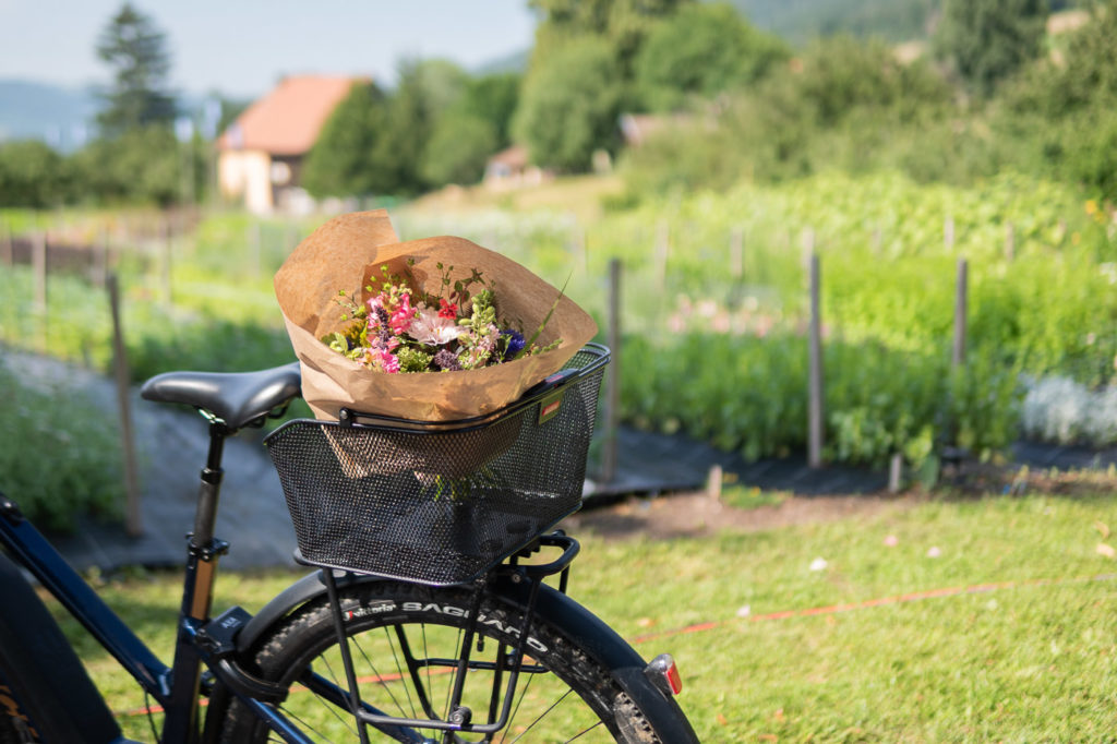Bouquet de fleurs fait main, emballé dans un papier kraft, dans le panier arrière d'un vélo.